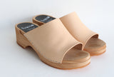 a pair of open toe slip on shoes with natural leather upper and wooden base
